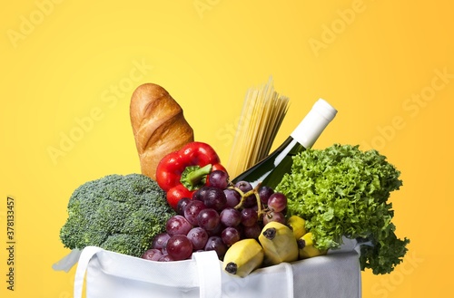 Full shopping bag with vegetable on colored background