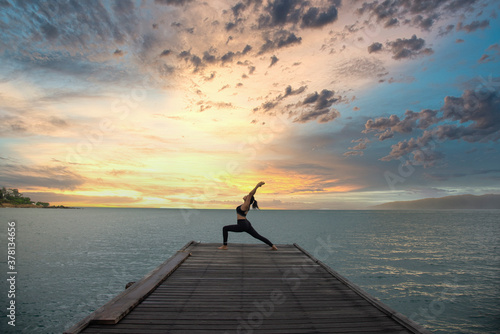 Young healthy woman practicing yoga on the bridge in the nature