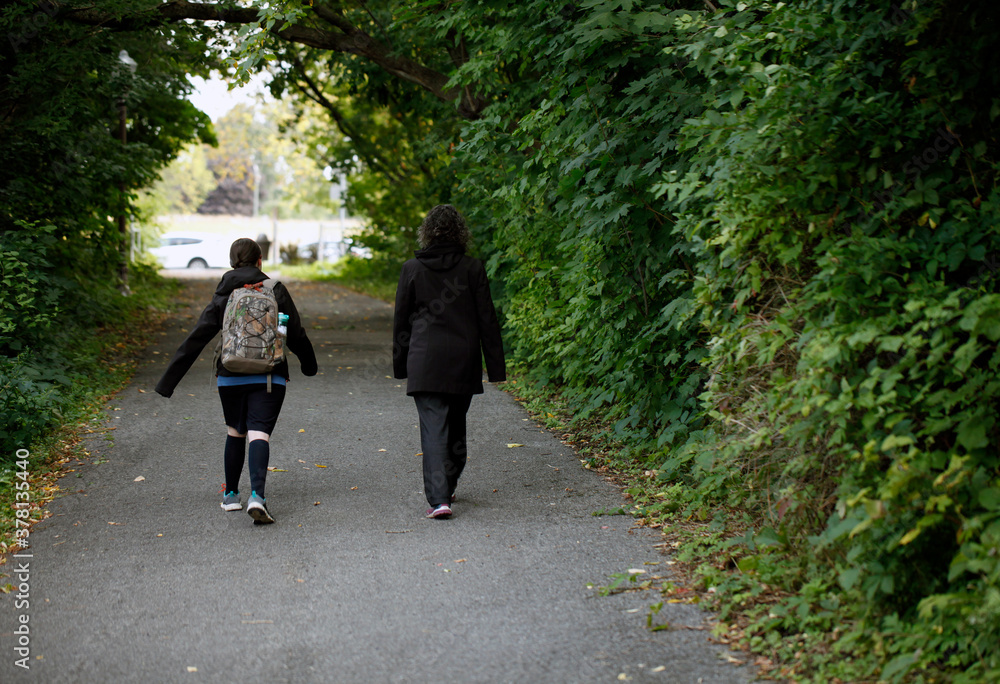 une mère et sa fille marchent dans un parc pour aller à l'école une mère et sa fille marchent dans un parc pour aller à l'école