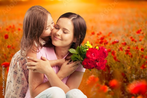 Happy beautiful mother and daughter hugging with a bouquet © BillionPhotos.com
