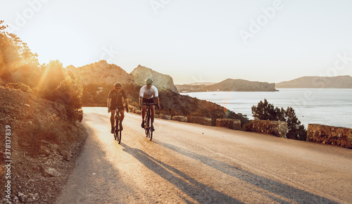 Two professional male cyclists riding their racing bicycles in the morning together