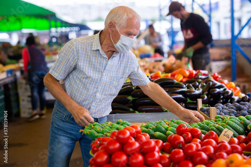 retired european man wearing medical mask protecting against virus buying tomatoes in market