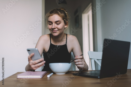 Happy woman messaging on smartphone in kitchen