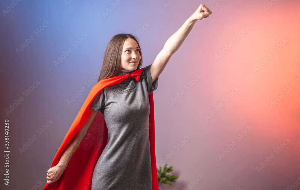 A young determined woman in a superhero cape has her hand up and is rushing forward. Blue and pink background