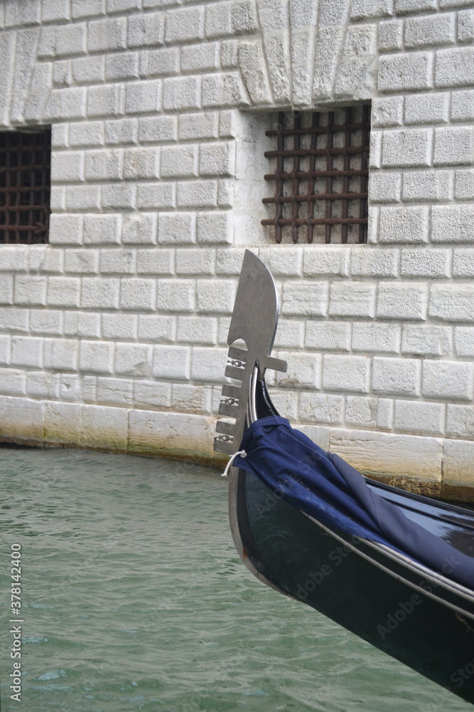 
prow of a gondola in Venice with a typical stone building in the background