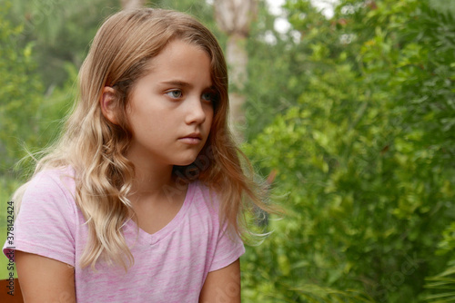 Closeup of girl outside with a neutral/sad expression, looking to the side
