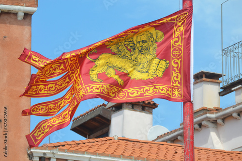 
flag of the old maritime republic of Venice called La Serenissima, depicts a yellow winged lion on a red background with a book between its paws. The book has a Latin inscription that says: "Peace to