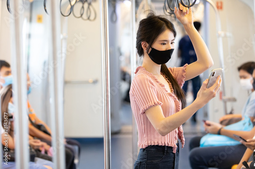 Fototapeta Naklejka Na Ścianę i Meble -  asian women wearing face mask, using smartphone in the train