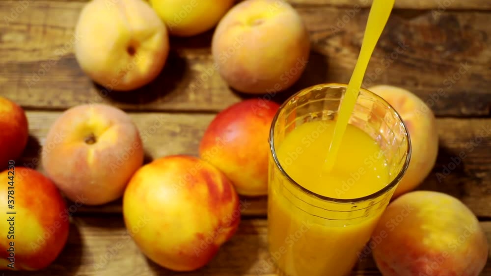 fruit juice is poured into a glass on a wooden table.close up. fruit juice is poured into a glass on a wooden table.close up.