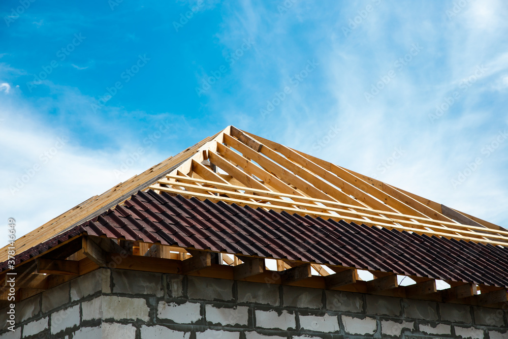 Installation of a wooden roof and Closing the roof with Onduvilla bituminous tiles. Woods elements and components of the construction of roof. Ceiling beams of natural eco-friendly materials.