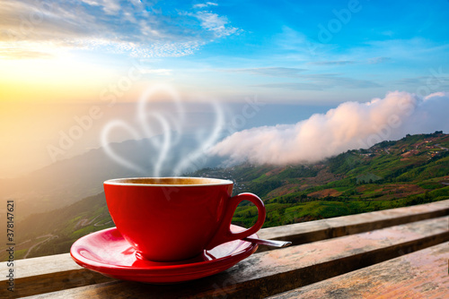 A cup of coffee with smoke on wood table, blurred estate scenic background, high angle view. Morning coffee cup
