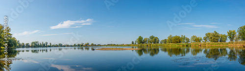 Fototapeta Naklejka Na Ścianę i Meble -  Panoramic view over a lake near Elbe river with wind turbines at sunny day and blue sky, Magdeburg, Germany..