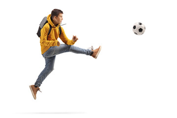 Male teenager jumping and kicking a soccer ball