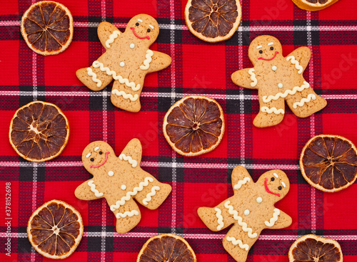 Gingerbread men with dried orange slices on a red tartan background. Top view.