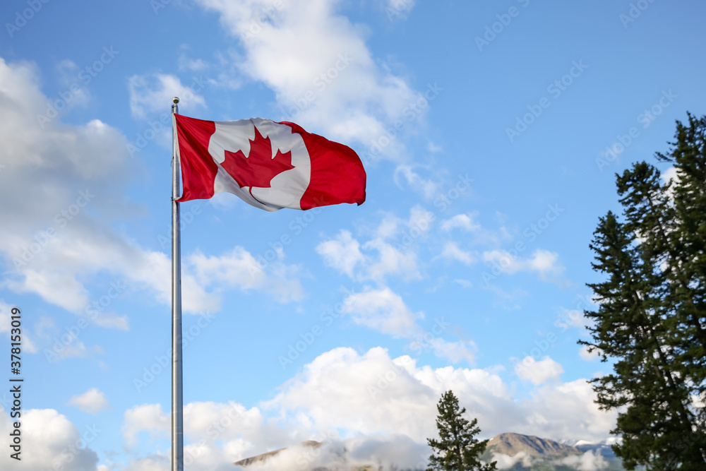 The national flag of Canada against a blue sky in the Canadian Rockies The national flag of Canada against a blue sky in the Canadian Rockies