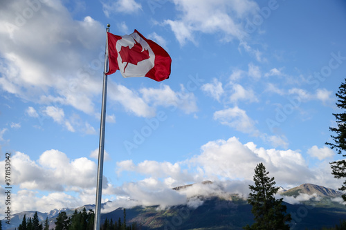 The national flag of Canada against a blue sky in the Canadian Rockies