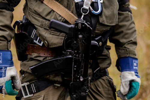 Close-up, Kalashnikov assault rifle, on the chest of a military man. There is a tint. Special forces team. Russian police (Spetsnaz).