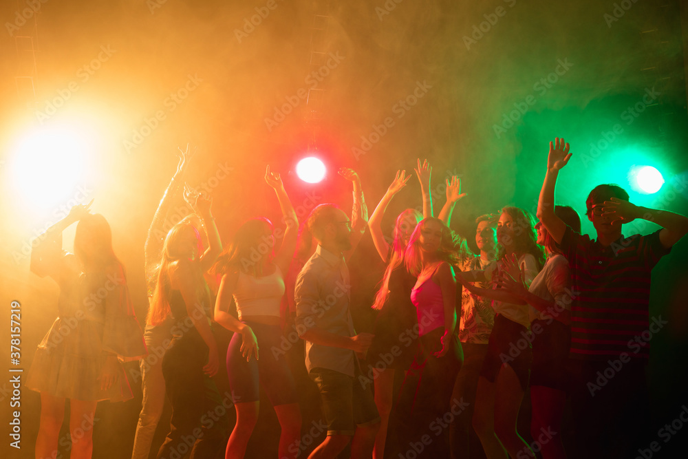 Party time. A crowd of people in silhouette raises their hands, dancing on dancefloor on neon light background. Night life, club, music, dance, motion, youth. Bright colors and moving girls and boys. Party time. A crowd of people in silhouette raises their hands, dancing on dancefloor on neon light background. Night life, club, music, dance, motion, youth. Bright colors and moving girls and boys.