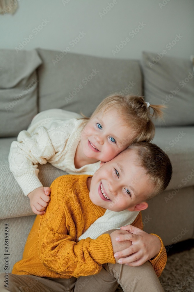 Little brother and sister in cozy knitted sweaters play at home. Portrait of cute little brother and sister. Fall. Little brother and sister in cozy knitted sweaters play at home. Portrait of cute little brother and sister. Fall.