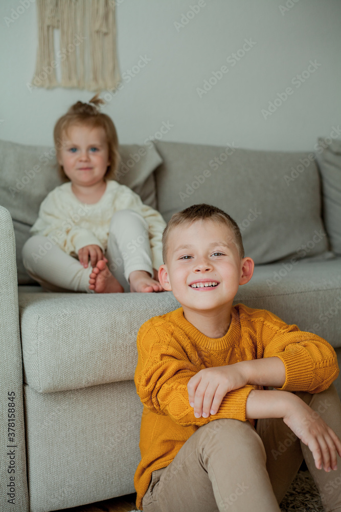 Little brother and sister in cozy knitted sweaters play at home. Portrait of cute little brother and sister. Fall. Little brother and sister in cozy knitted sweaters play at home. Portrait of cute little brother and sister. Fall.