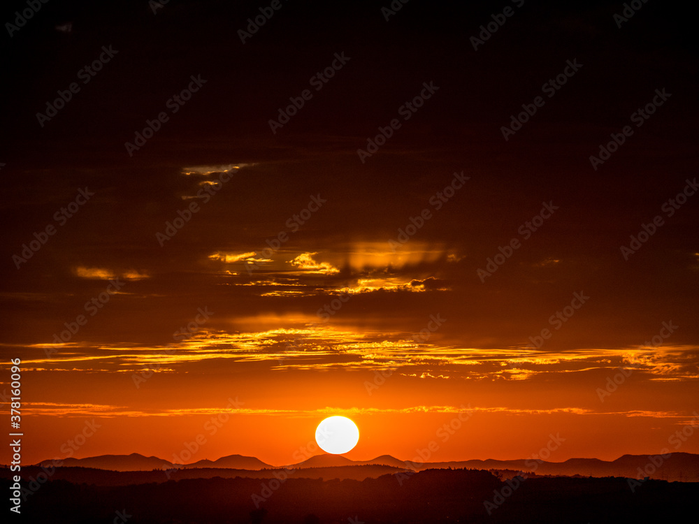Obraz premium Sonnenuntergang hinter Hügelkette