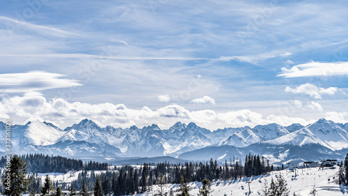 Panoramic view on snowy forest and Tatra Mountains in winter time. Ski slopes and ski lifts in Bialka Tatrzanska, Poland