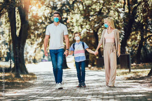 Mother,father and little son wearing face protective medical mask for protection from virus disease in park.
