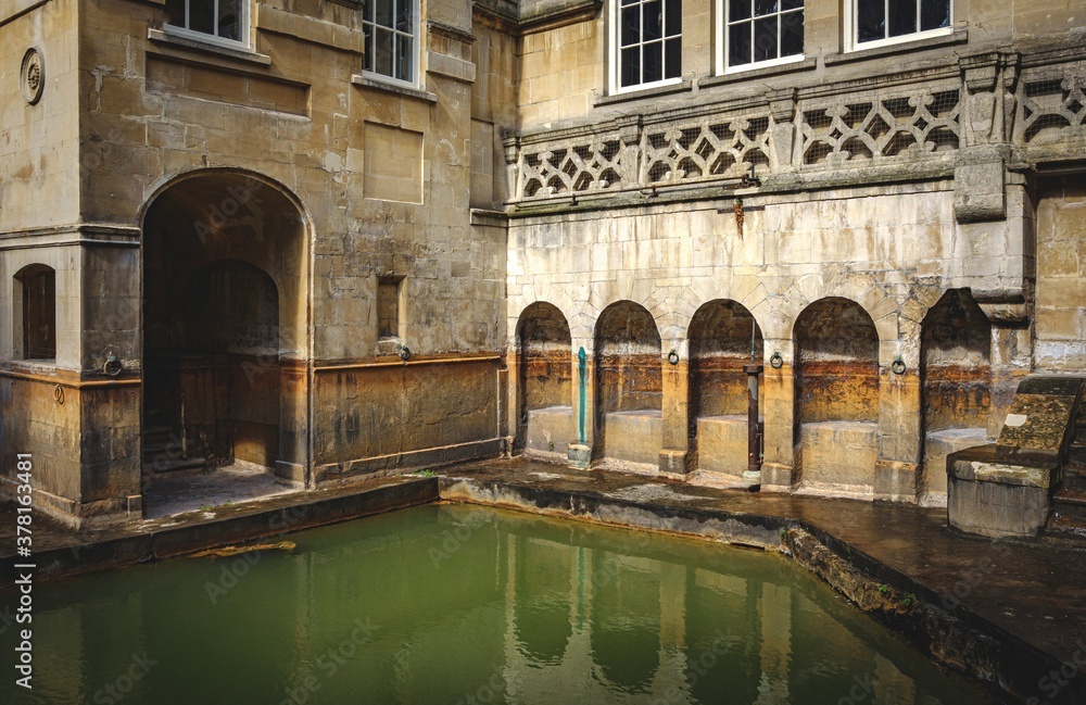 water and buildings in an old roman bath in the city of Bath in the united kingdom
