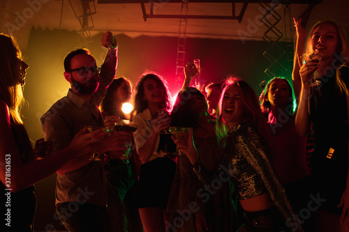 Drive. A crowd of people in silhouette raises their hands, dancing on dancefloor on neon light background. Night life, club, music, dance, motion, youth. Bright colors and moving girls and boys.