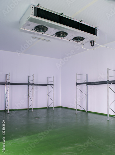 Empty cold room for food, with storage shelves and a refrigerator evaporator machine to produce cold and preserve the food photo