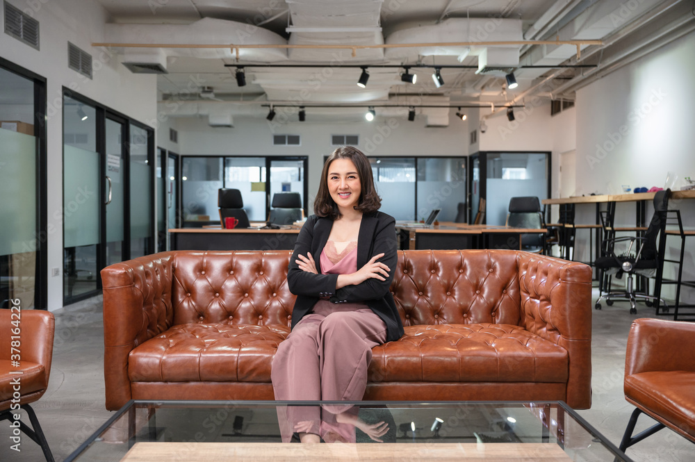Obraz premium Asian woman entrepreneurs confident sitting and smiling on vintage sofa in coworking space at office