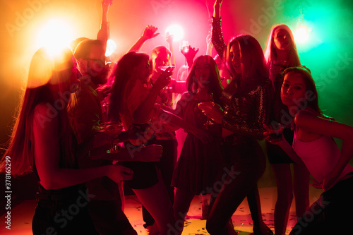 Energy. A crowd of people in silhouette raises their hands, dancing on dancefloor on neon light background. Night life, club, music, dance, motion, youth. Bright colors and moving girls and boys.