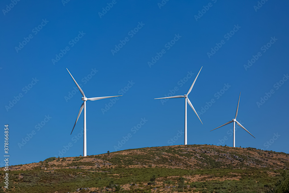 View of a wind turbines on top of mountains, ecological and environmental theme View of a wind turbines on top of mountains, ecological and environmental theme