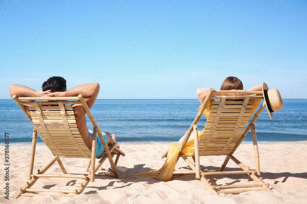 Woman and her boyfriend on deck chairs at beach. Lovely couple Woman and her boyfriend on deck chairs at beach. Lovely couple