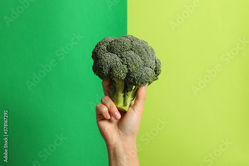 Female hand hold broccoli on two tone background