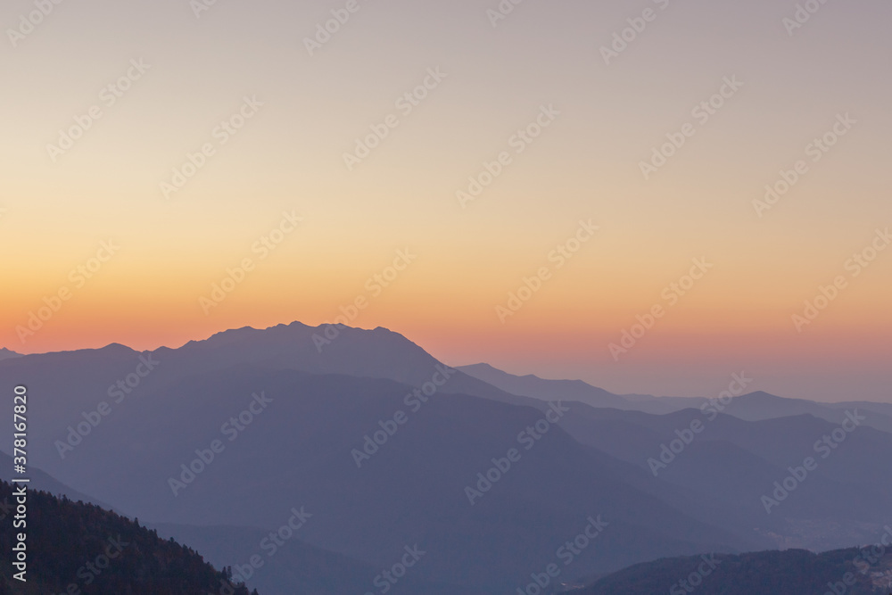 A scenic sunset in the mountains with sunlight, beautiful light. Evening summer landscape in a valley with horizon, sky, grass, flowers. Hiking and trekking.