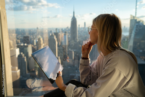 Foto Thoughtful female digital nomad with modern touch pad looking in panoramic windo