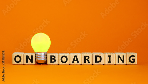 Wooden cubes with word 'onboarding'. Yellow light bulb. Beautiful orange background. Business concept. Copy space. photo