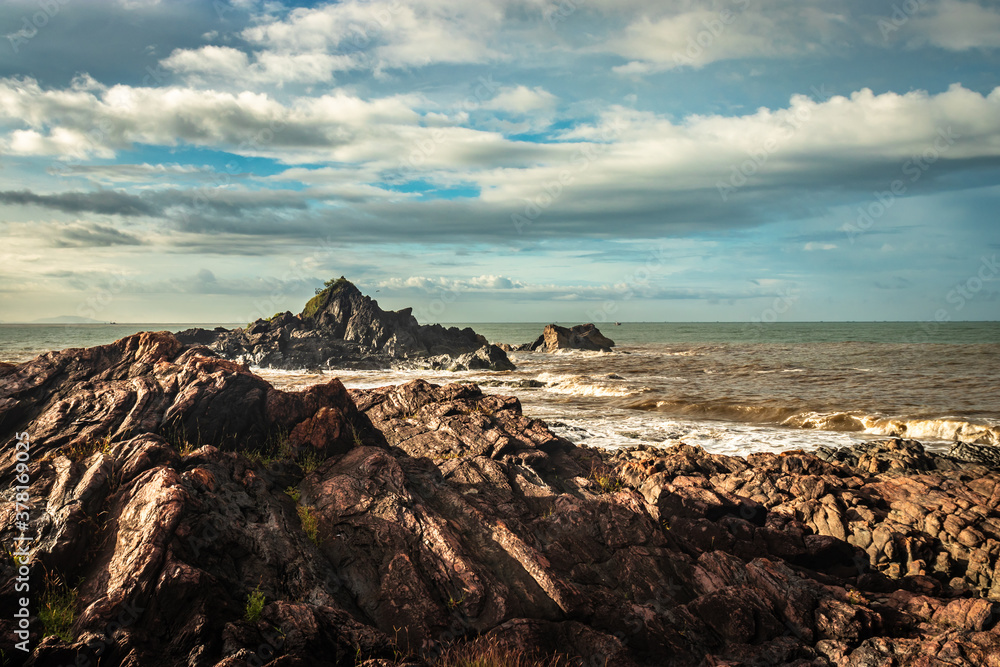 Fototapeta premium rocky sea beach with crashing waves at morning from flat angle