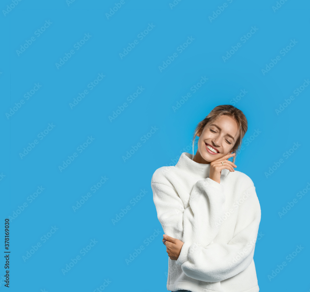 Beautiful young woman wearing knitted sweater on light blue background. Space for text Beautiful young woman wearing knitted sweater on light blue background. Space for text