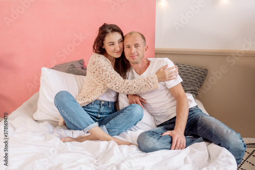 Man and woman hugging while sitting on the bed in the bedroom 