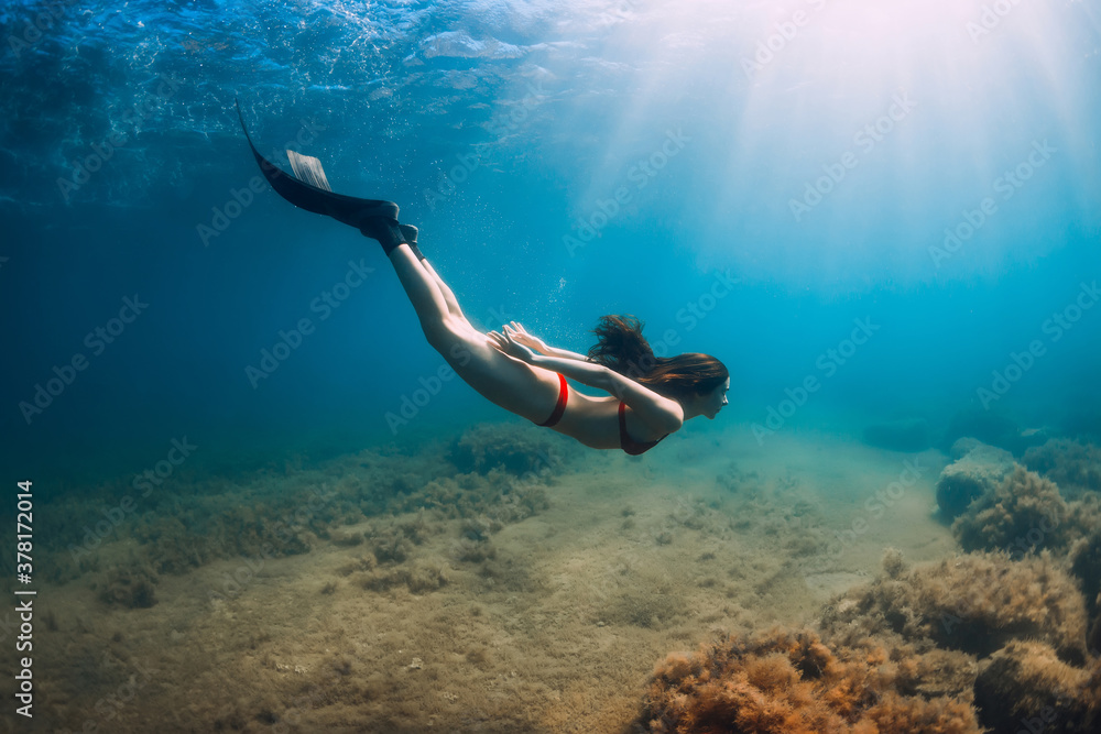 Freediver woman in bikini glides in blue sea and sun rays. Freediving with  fins underwater in ocean Stock-Foto | Adobe Stock
