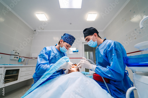 Surgery dental operation. Two dentists provide stomatology operation. Dental clinic. Selective focus.