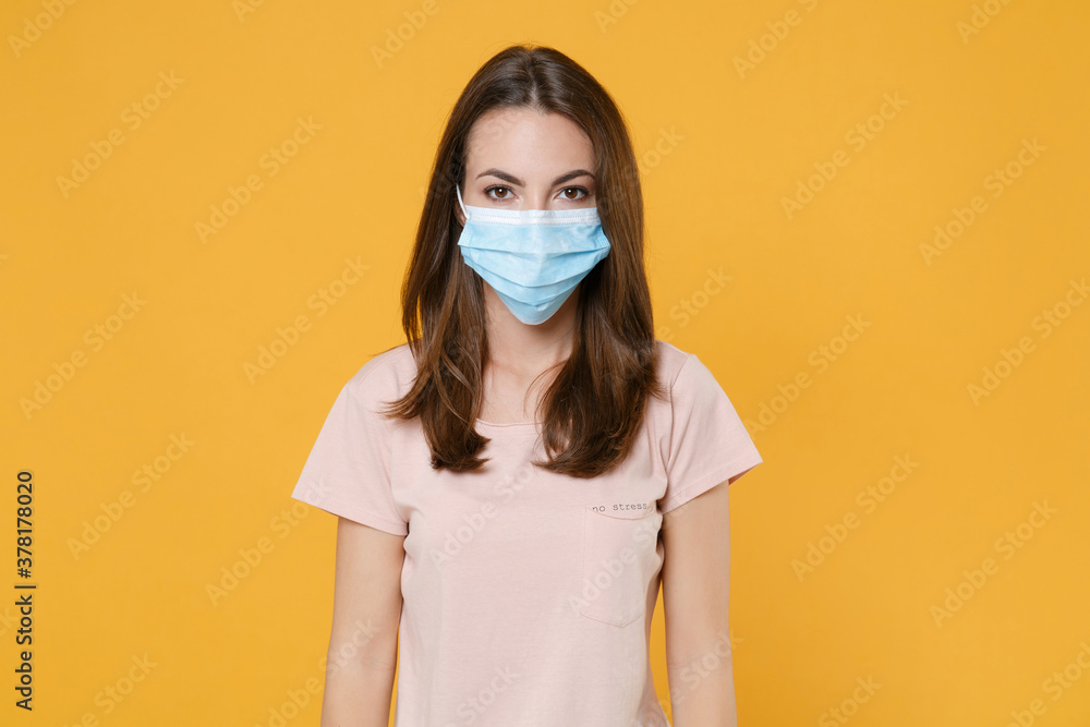 Young brunette woman in pastel pink casual t-shirt sterile face mask to safe from coronavirus virus covid-19 2019-ncov looking camera isolated on bright yellow color wall background studio portrait. Young brunette woman in pastel pink casual t-shirt sterile face mask to safe from coronavirus virus covid-19 2019-ncov looking camera isolated on bright yellow color wall background studio portrait.