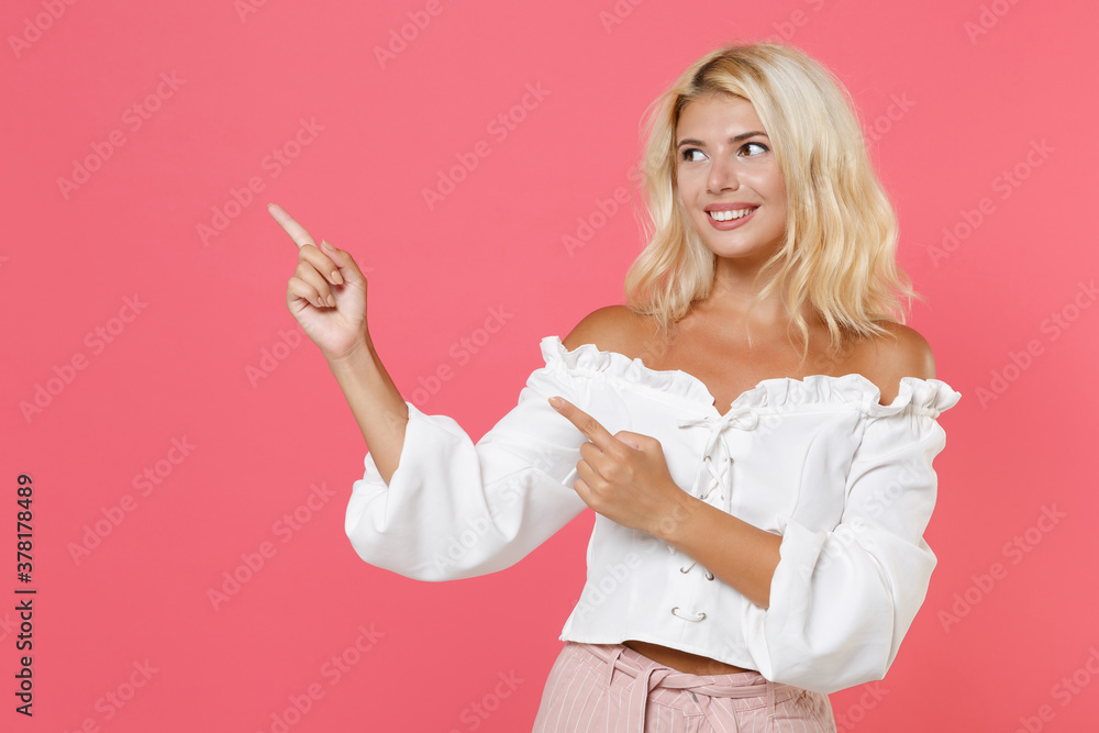 Smiling pretty attractive young blonde woman 20s in white casual clothes standing pointing index fingers aside up on mock up copy space isolated on bright pink colour background, studio portrait. Smiling pretty attractive young blonde woman 20s in white casual clothes standing pointing index fingers aside up on mock up copy space isolated on bright pink colour background, studio portrait.