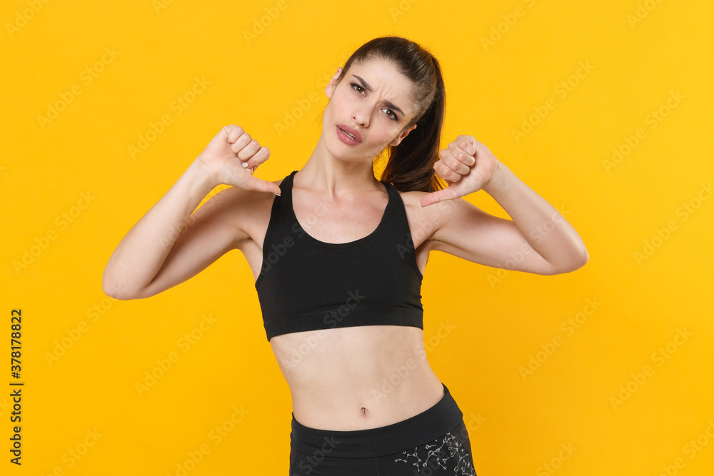 Puzzled confident young fitness sporty woman 20s in black sportswear posing training working out pointing thumbs on herself looking camera isolated on bright yellow color background studio portrait. Puzzled confident young fitness sporty woman 20s in black sportswear posing training working out pointing thumbs on herself looking camera isolated on bright yellow color background studio portrait.