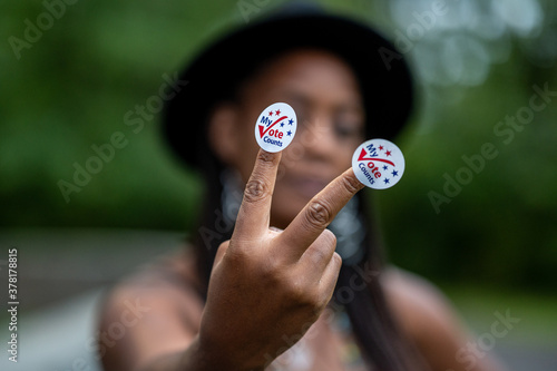 Black Woman Holding A Pair of My Vote Counts Stickers photo
