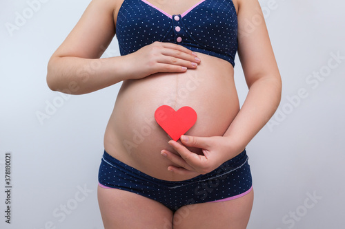 Wallpaper Mural A pregnant woman holds a heart symbol against the background of her stomach Torontodigital.ca
