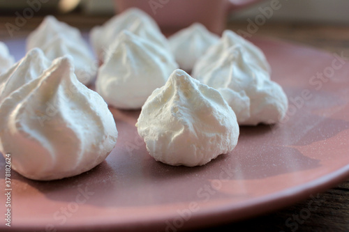 Close-up of meringue on a pink plate. Marshmallows on pink background