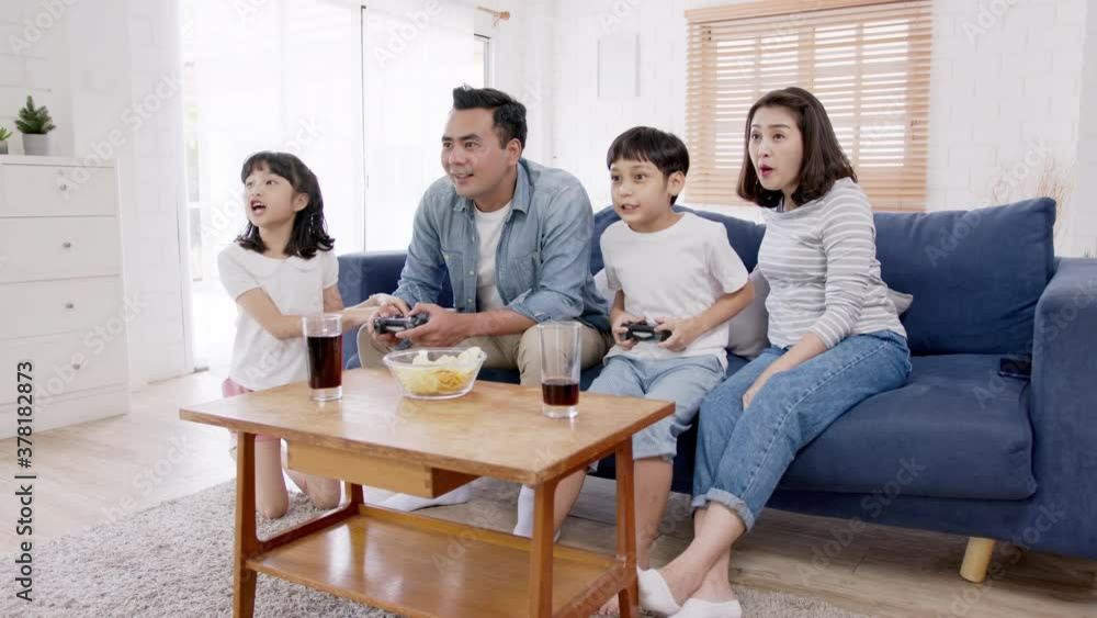 Wide shot happy asian family play video game at home feeling excited fun holding console in hand in quarantine activity, entertainment at home concept. Competition and funny in leisure time or hobby. Wide shot happy asian family play video game at home feeling excited fun holding console in hand in quarantine activity, entertainment at home concept. Competition and funny in leisure time or hobby.